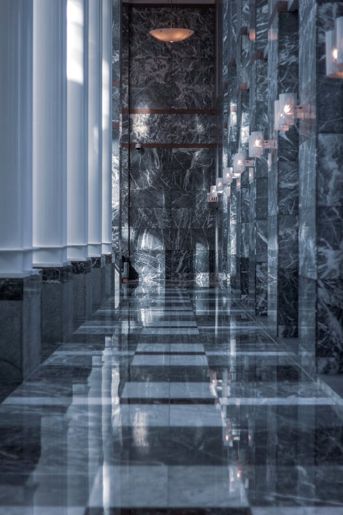 about-01 Sleek modern hallway featuring marble walls and floor with reflective surfaces and soft lighting.